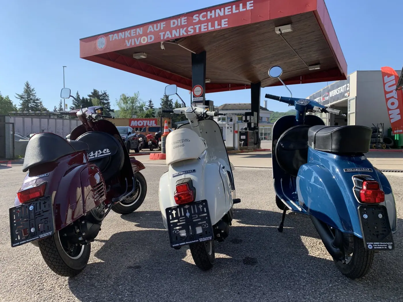 Drei Vespa-Roller an der Tankstelle